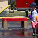 This youngster, two-year-old Beau Burglar, looks back on a sheet of falling water from the fire department's ladder truck.